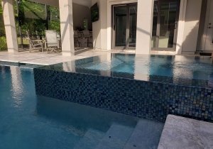 Perimeter overflow spa with slot detail, sliver travertine decking with infinity edge coping and glass tile spa/waterline